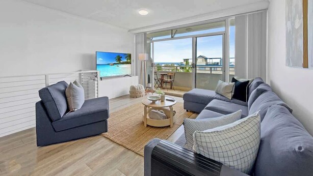 A modern living room with a sofa set, a coffee table, and a TV.