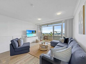 A modern living room with a sofa set, a coffee table, and a TV. - Views by Day, Waves at Night on Kings Beach (Caloundra Region)