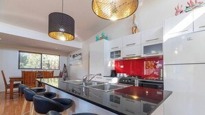 Cozinha moderna com ilha central, eletrodomésticos de aço inoxidável e uma parede de destaque vermelha.