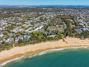 An aerial view of a coastal residential area with houses, a beach, and a clear sky.