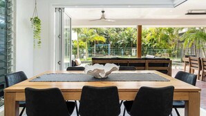 A dining area with a wooden table, black chairs, and a decorative bowl centerpiece. - Golden Beach Luxury for Families (Caloundra Region)