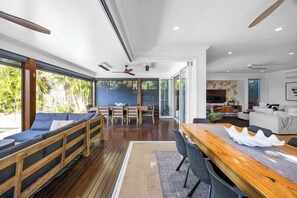 Un intérieur moderne avec une terrasse en bois, un coin repas et un espace de vie doté d’une télévision et d’une cheminée.