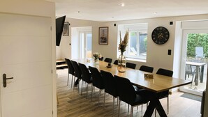 Een moderne eetruimte met een grote houten tafel, zwarte stoelen en een vaas met bloemen.