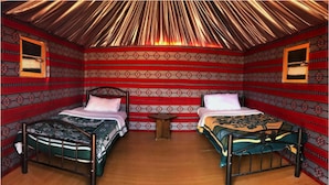 A room with two beds, a small table, and patterned walls. - Wadi Rum Heritage (Wadi Rum)