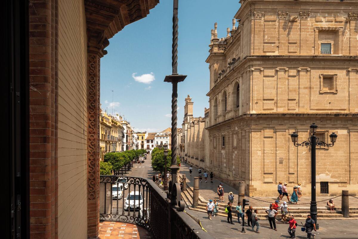 A historic building with ornate architecture, a street with pedestrians, and a clear sky.