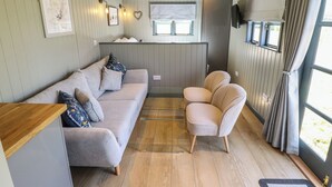 Un ambiente acogedor con un sofá, sillones, una mesita y una ventana con cortinas.