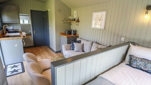 Una habitación compacta con kitchenette, un sofá, una cama y una pequeña mesa.