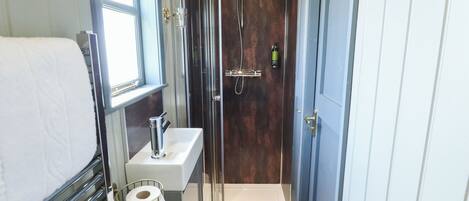 A compact bathroom with a shower, a sink, and a toilet.