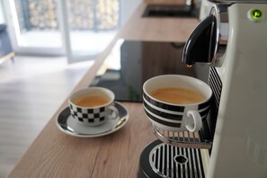 Une machine à café verse du café dans deux tasses posées sur une table en bois.