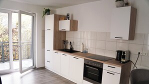 A modern kitchen with white cabinets, a wooden countertop, and a built-in oven.
