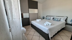 Ein Hotelzimmer mit Bett, Kissen, Nachttisch und Spiegel.