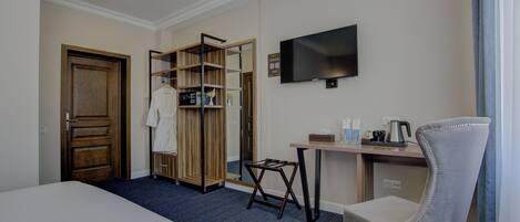 A hotel room with a bed, a desk, a chair, a TV, a wardrobe, and a mirror.