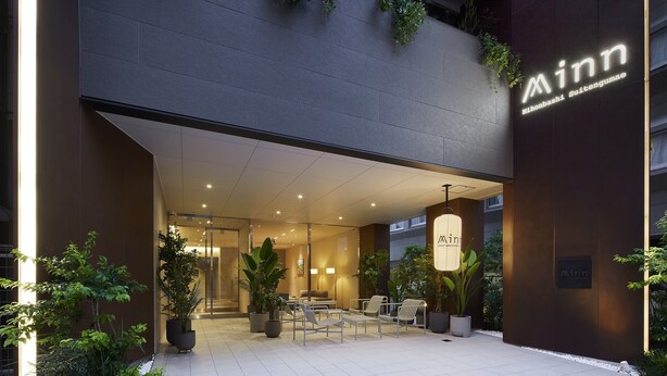 A hotel entrance with a modern design, featuring a glass facade, outdoor seating area, and potted plants. - Minn Nihonbashi Suitengumae (Tokyo)