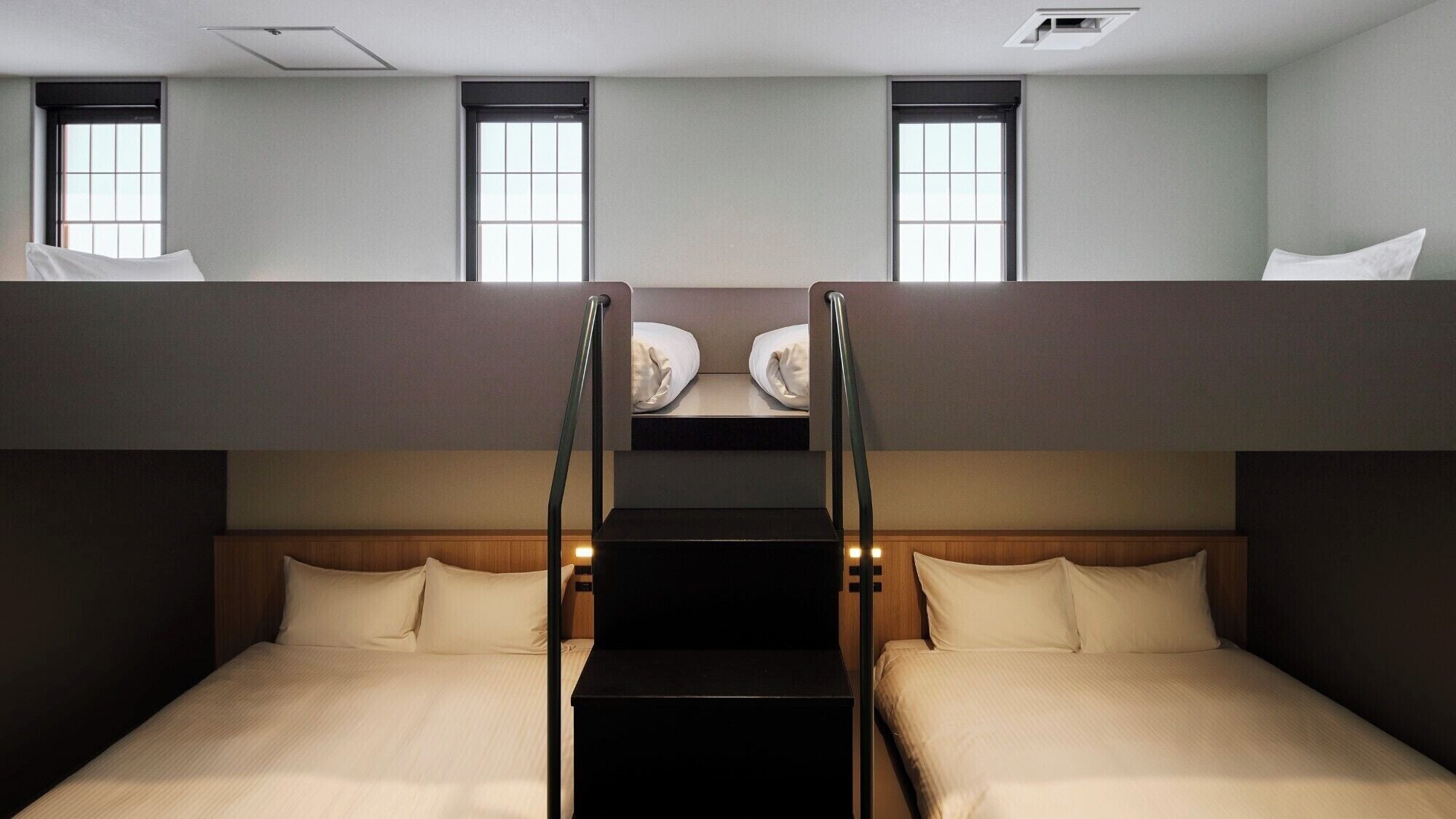 A bunk bed room with two beds, a staircase, and windows.