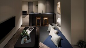 A modern living room with a sofa, coffee table, and two bar stools. - Minn Nihonbashi Suitengumae (Tokyo)