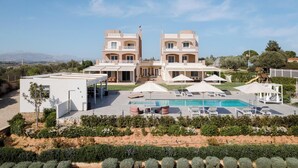 A modern hotel with a pool, outdoor seating, and a view of the mountains. - Ema's Guest House (Markopoulo Mesogaias)