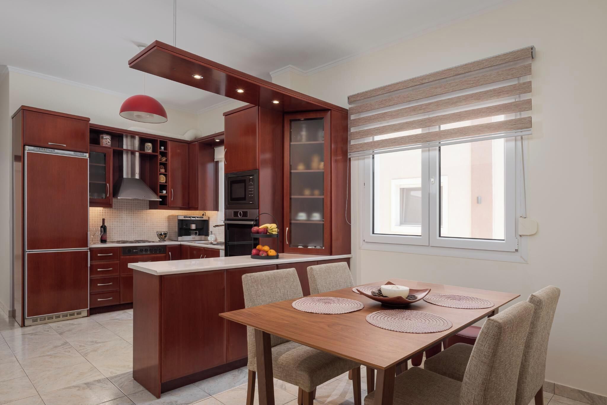 Une cuisine moderne avec des meubles en bois, un îlot central et un coin repas comprenant une table et des chaises.
