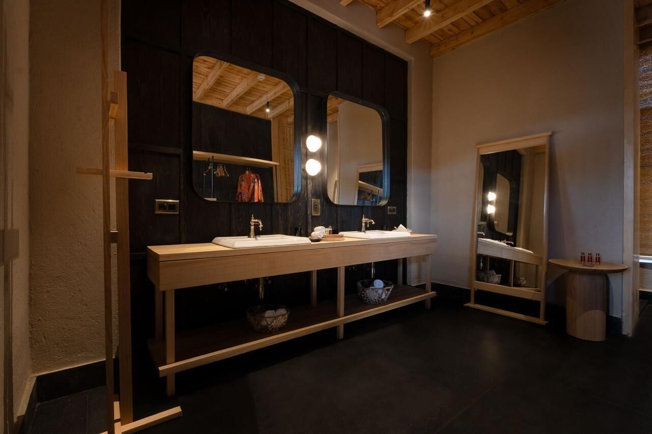 Un baño moderno con tocador de madera oscura, dos lavamanos y espejos grandes.