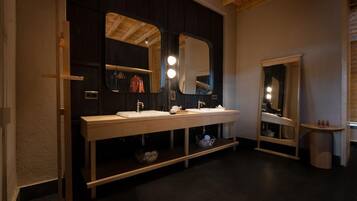 Un baño moderno con tocador de madera oscura, dos lavamanos y espejos grandes.