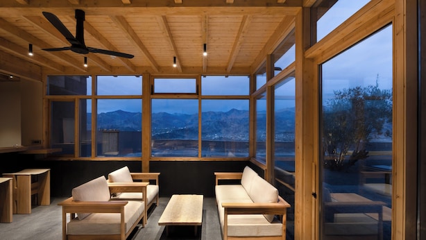 Un intérieur moderne avec des meubles en bois, de grandes fenêtres et un ventilateur de plafond.