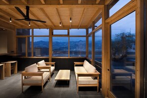 Un interior moderno con muebles de madera, ventanas amplias y un ventilador de techo.