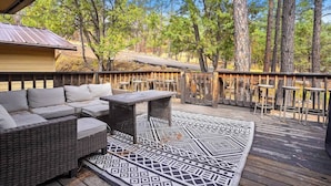 A deck with outdoor furniture, including a sofa and a table, surrounded by a wooden railing.