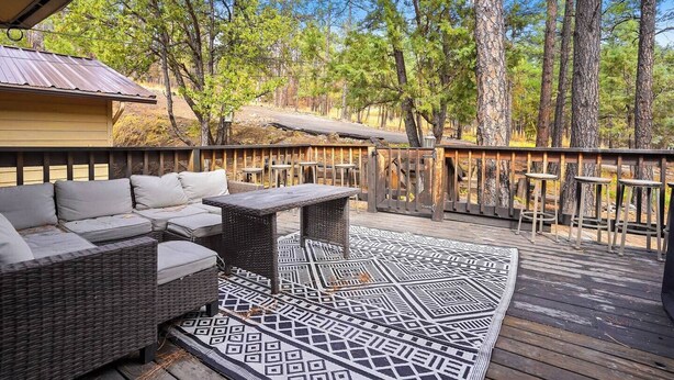 A deck with outdoor furniture, including a sofa and a table, surrounded by a wooden railing.