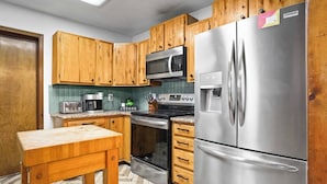 A kitchen with wooden cabinets, stainless steel appliances, a microwave, a refrigerator, and a coffee maker.
