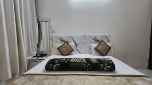 Een net opgemaakt bed met een bedsprei met patroon, twee kussens met een geometrisch ontwerp, en een marmeren hoofdbord.