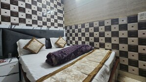 Een net opgemaakt bed met een bedspreide met patroon, een hoofdbord en kussens.