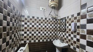 Een badkamer met een wand betegeld met zwart-wit schaakbordpatroon, een wit wastafelmeubel en een toilet.