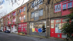 A row of red-framed buildings with large windows and a car parked in front.
