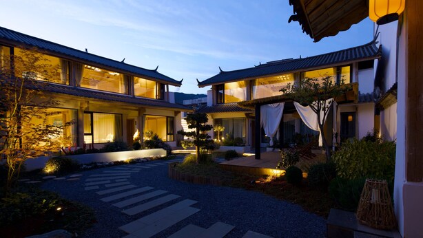 A traditional Japanese-style building with multiple connected structures, a landscaped garden with a pathway, and a lantern. - Jinghua Inn (Lijiang)