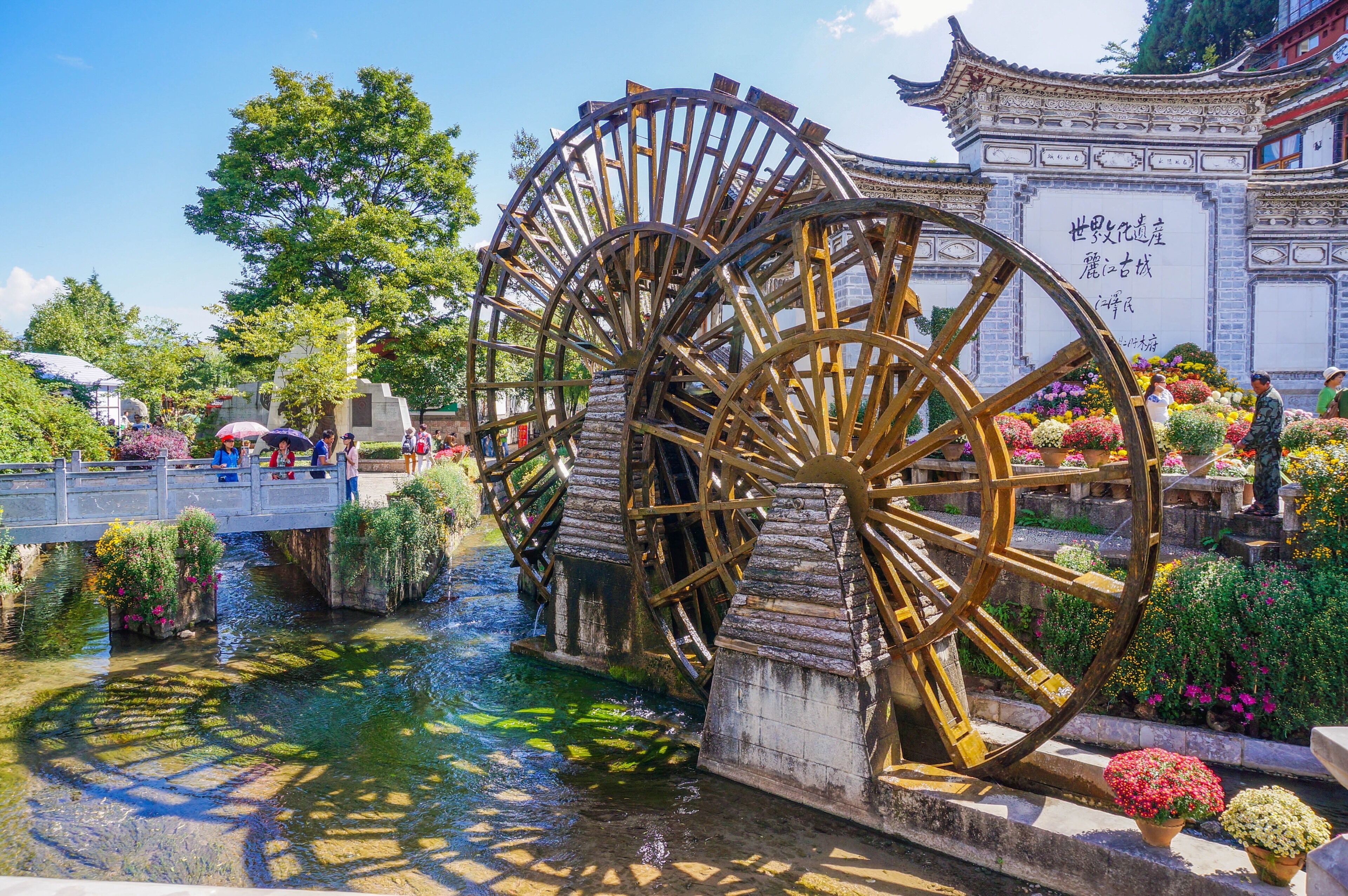 A traditional water wheel structure with a bridge and flower arrangements.