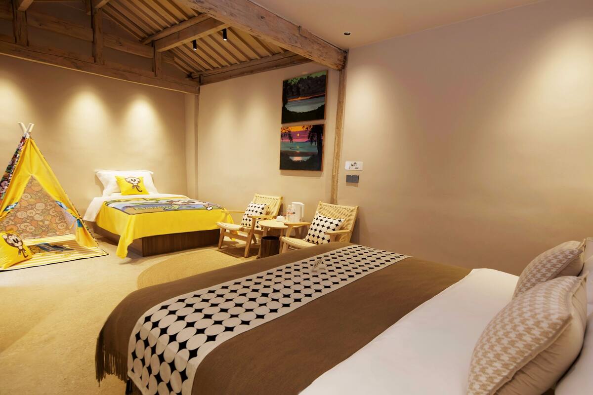 Ein gemütliches Schlafzimmer mit Bett, einem kleinen Tisch, zwei Stühlen, einem Zelt und einem Bild an der Wand.
