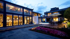 A modern building with large glass windows, a courtyard with a dining area, and traditional architectural elements. - Jinghua Inn (Lijiang)