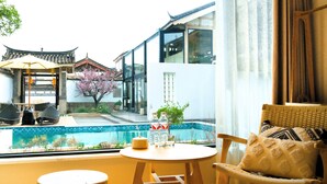 A modern room with a view of a traditional building, a small pool, and a dining area with outdoor furniture. - Jinghua Inn (Lijiang)