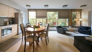 Eine moderne Küche mit Essbereich, großen Fenstern und einem Wohnbereich mit Sofa und Lampe.