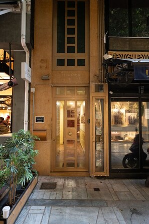 Un bâtiment avec une porte en bois et une entrée en verre, une enseigne indiquant un restaurant, et un pot de fleurs à l’extérieur.