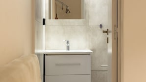 Une salle de bain avec un meuble-lavabo blanc, un miroir et un porte-serviettes.