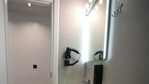 Une petite salle de bain avec un lavabo blanc, un miroir et des toilettes.