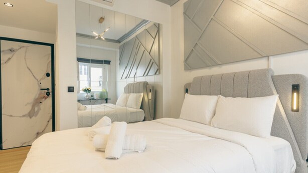Une chambre d’hôtel moderne avec un grand lit, un miroir et une vue sur la ville.