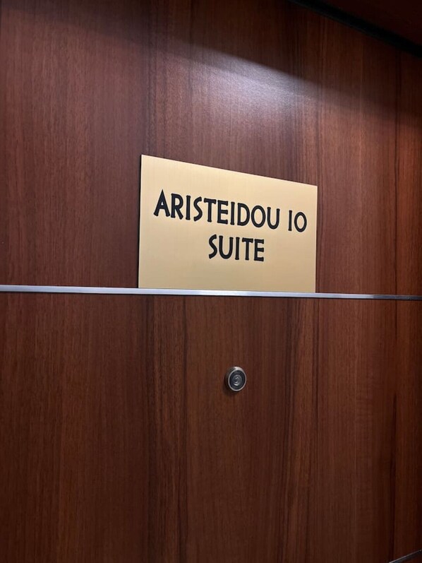 A wooden panel with a sign reading "ARISTEIDOU IO SUITE".