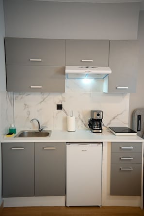 Een koffiezetapparaat/waterkoker, kookgerei, borden en bestek