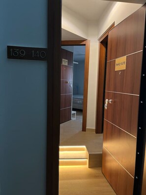A hotel corridor with a wooden door labeled "Family Suite" and a staircase leading to another room. - Family Suite by Zeussuites (Athina)