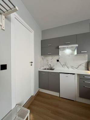 A modern kitchen with grey cabinets, a white countertop, and a built-in dishwasher. - Family Suite by Zeussuites (Athina)