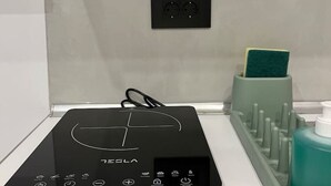 A black Tesla charging station on a white countertop with a green soap dispenser and a toothbrush holder.
