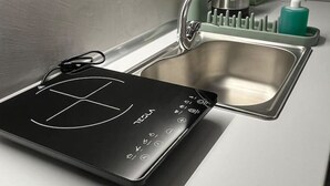 A kitchen with a built-in induction cooktop, a stainless steel sink, and a green kettle. - Muses Suite by Zeus suites (Athina)