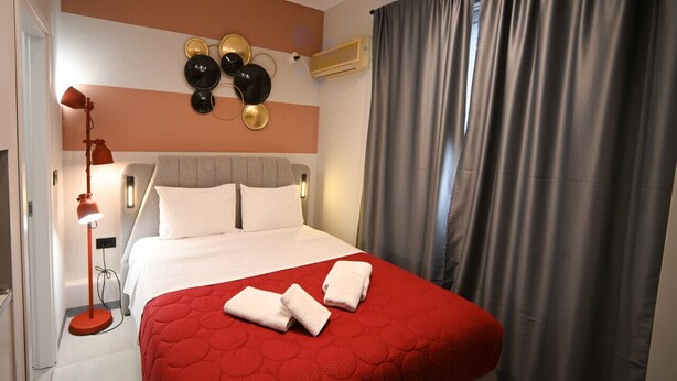 Ein Hotelzimmer mit einem Bett, einer Lampe, einer Wandklimaanlage und einem Vorhang.
