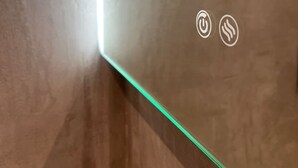 Ein Korridor mit grüner Neonbeleuchtung am Boden, zwei Symbole für eine Steckdose und eine Heizung.